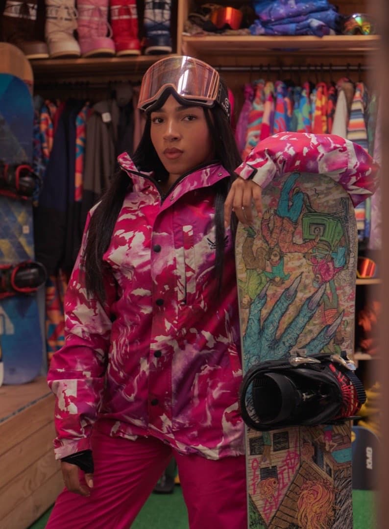 Mulher com roupa de neve rosa e snowboard colorido